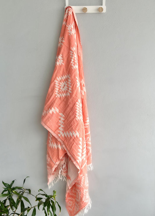 An orange beach towel hanging on a stand, showcasing its vibrant color and soft texture, ready for a day at the beach.